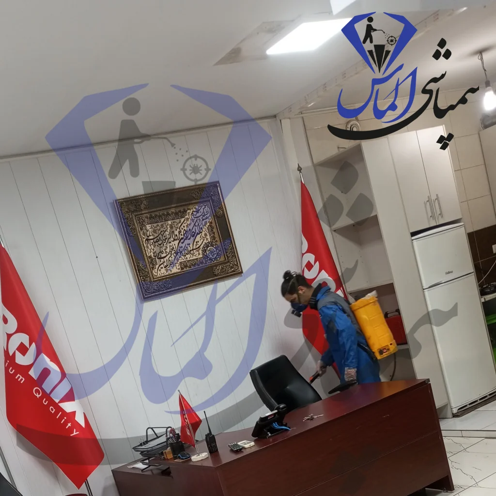 Person disinfecting office workspace with sprayer, red Ronix promotional flags in background, pest control service.